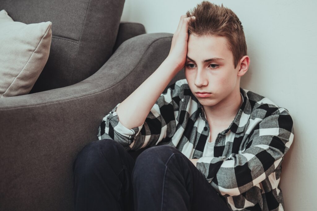 Teenager sitting thoughtfully on the floor indoors